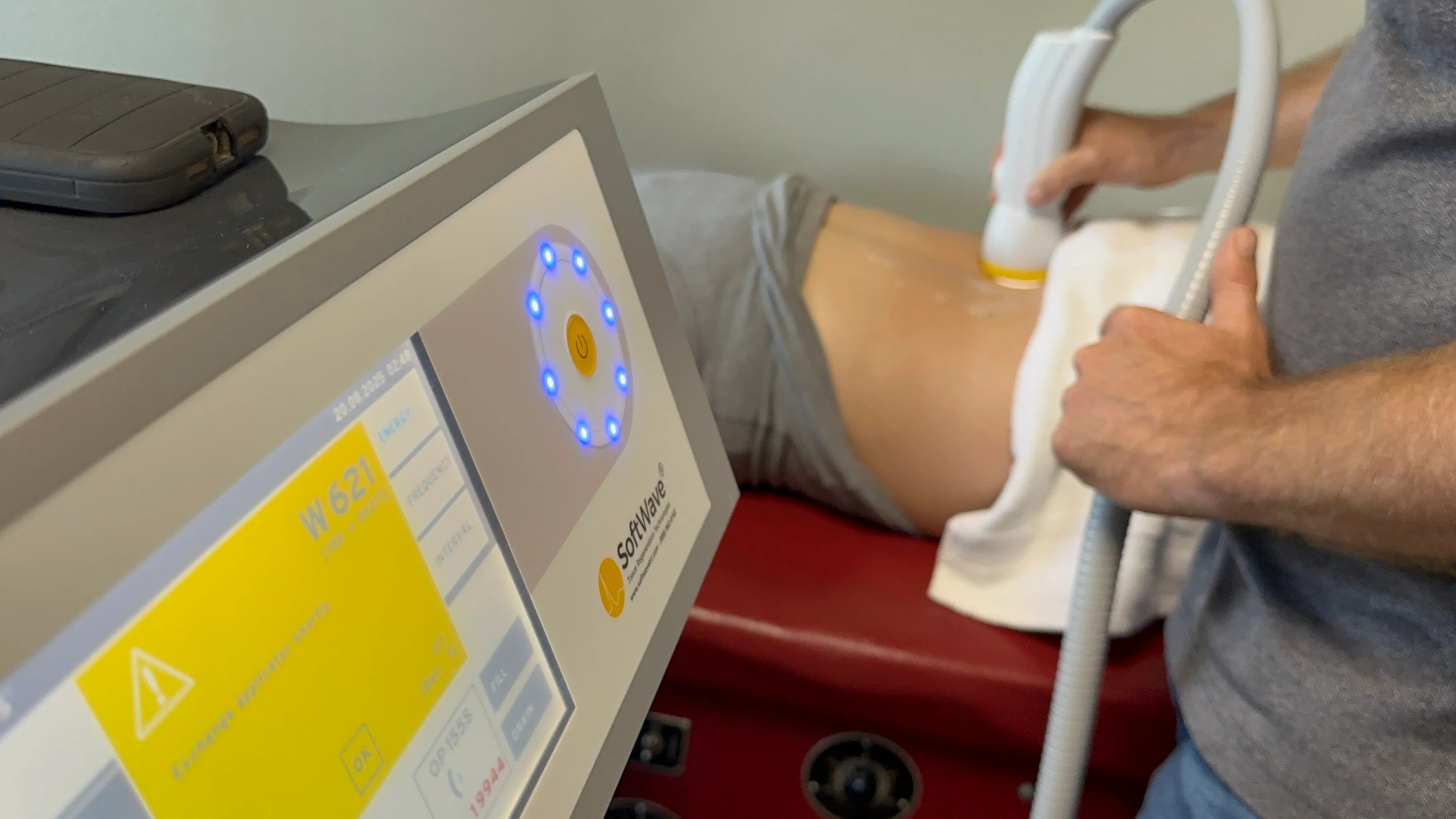 SoftWave therapy device and handheld applicator being used during an in-clinic treatment